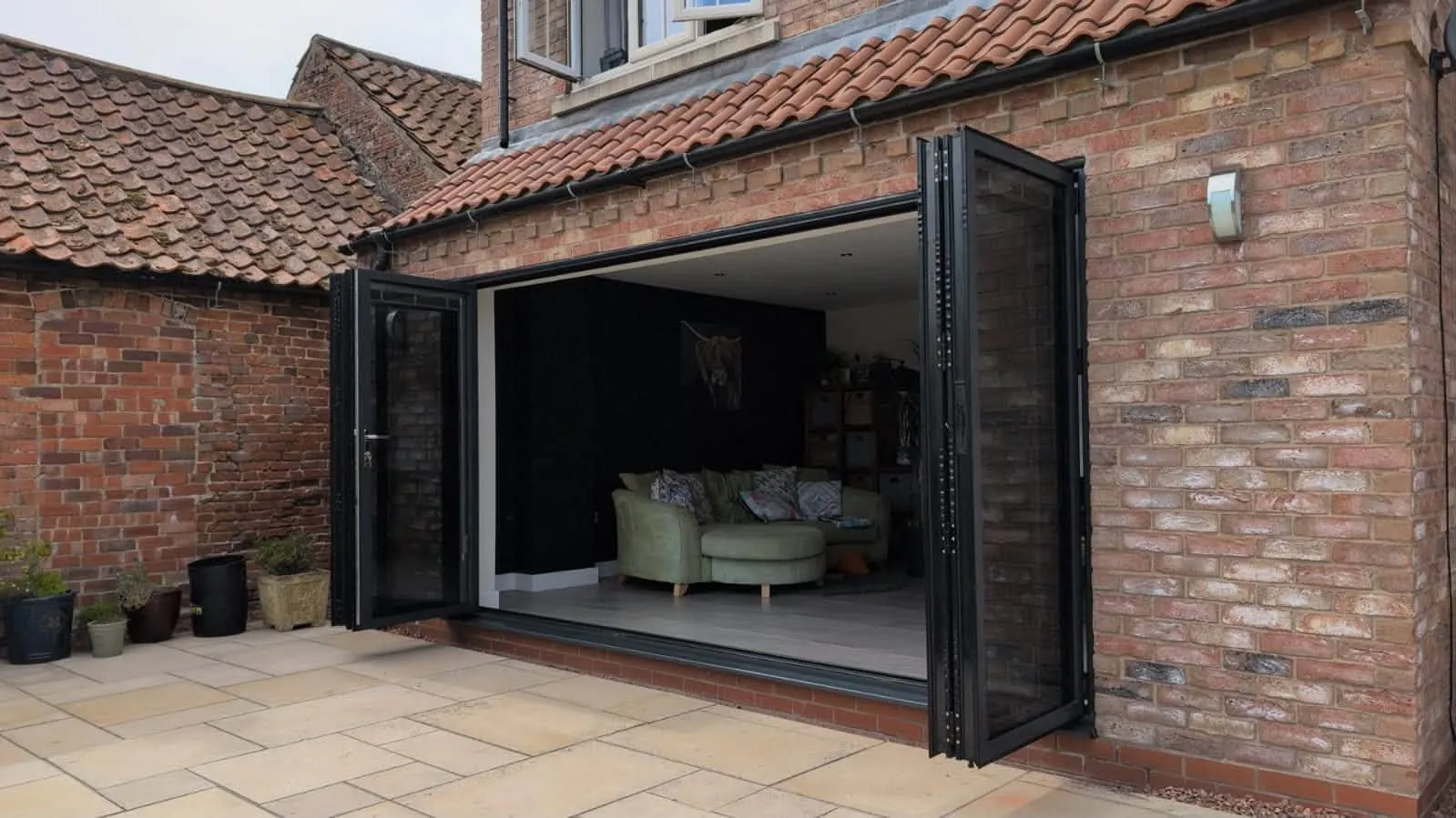 Aluminium bifold doors folded fully open, connecting the living room to the patio