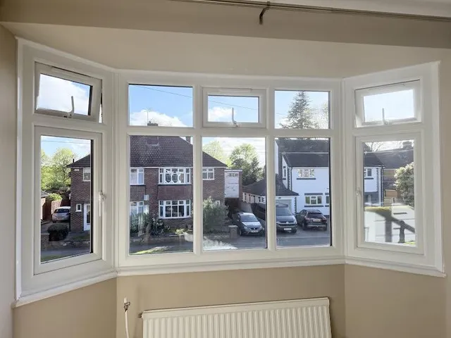 New white UPVC bay window with top-opening vents replacing blown double glazing